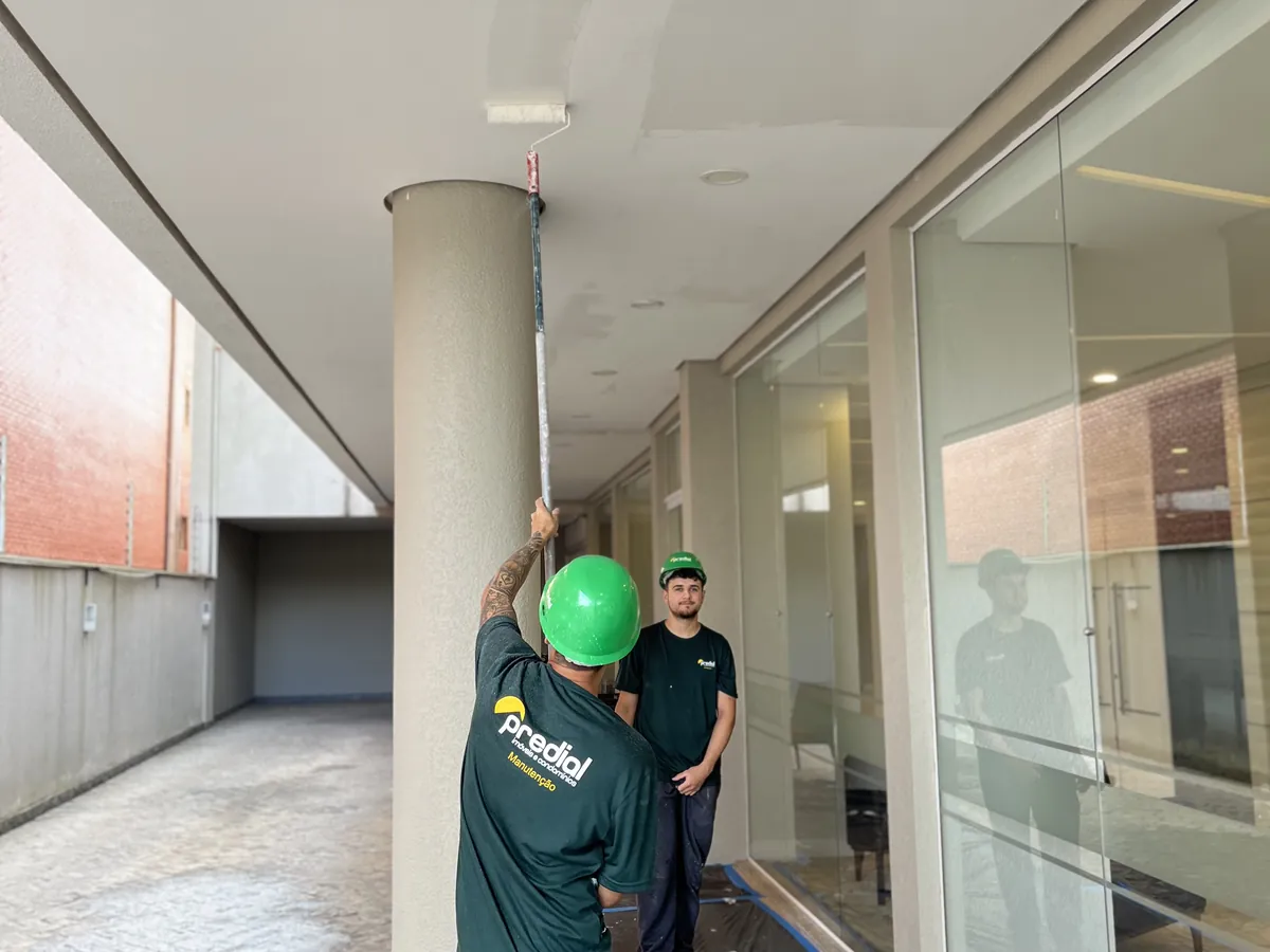 Equipe do Grupo Predial com capacetes pintando o teto de área externa com rolo extensor