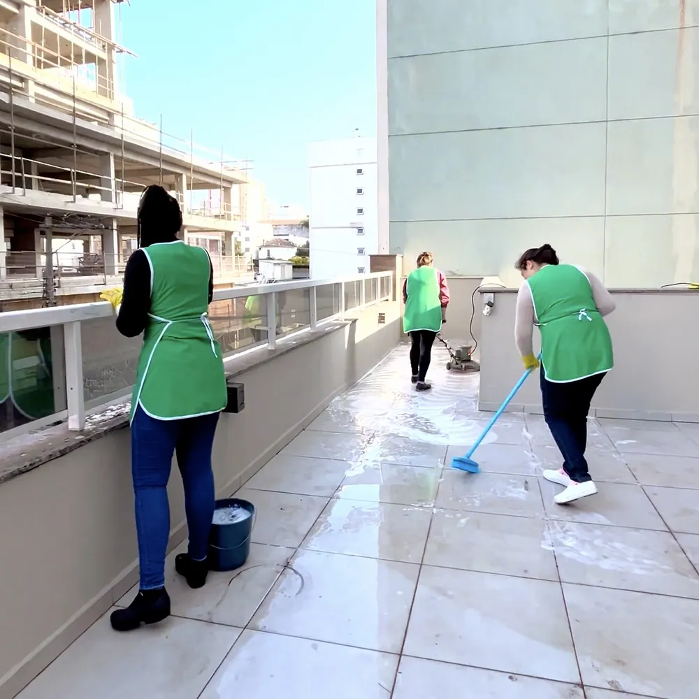 Colaboradoras do Grupo Predial lavando o piso da área externa de um condomínio