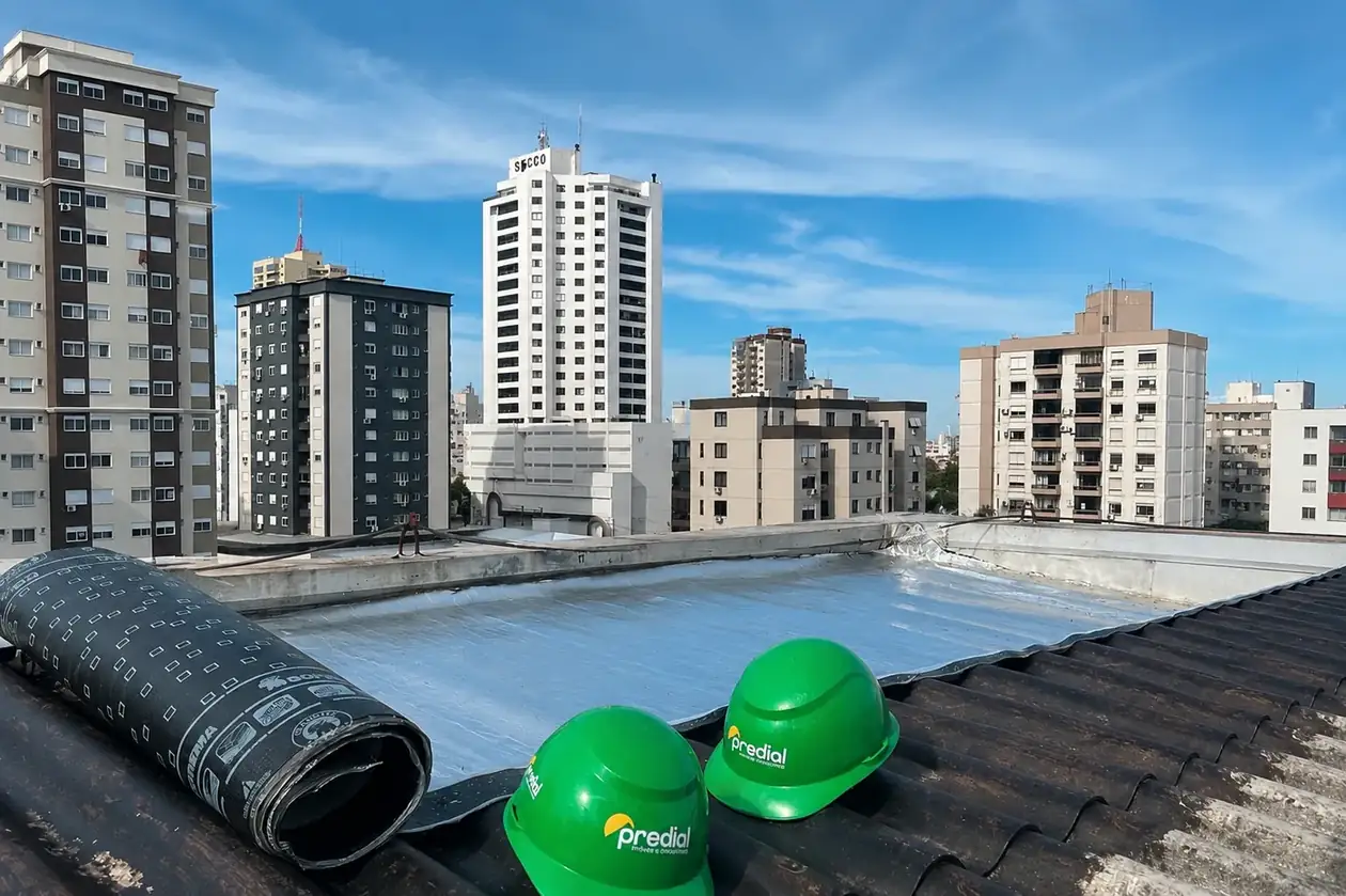Capacetes verdes do Grupo Predial sobre cobertura de edifício, com a cidade ao fundo
